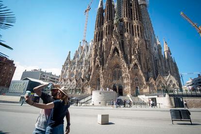 Una pareja se fotografía ante una Sagrada Familia casi vacía en Barcelona.