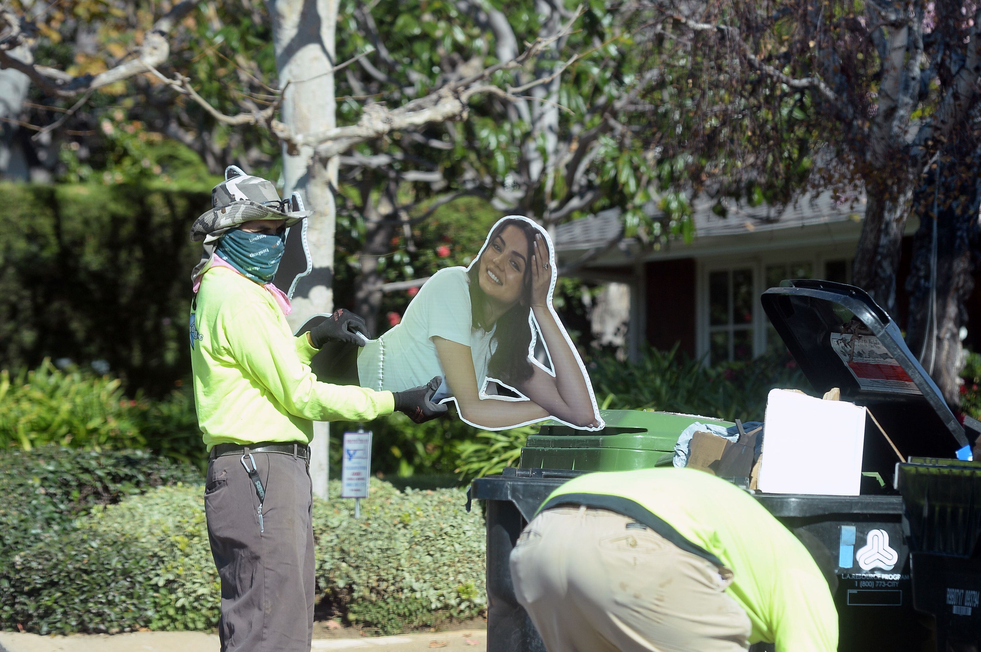 Un miembro del equipo de limpieza deposita un cartel de Ana de Armas en la basura frente a la casa de Ben Affleck, en Los Ángeles el pasado lunes.