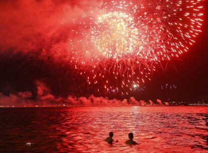 Dos chicos presencian desde el agua los fuegos artificiales en la playa de Flamengo, Rio de Janeiro (Brasil).