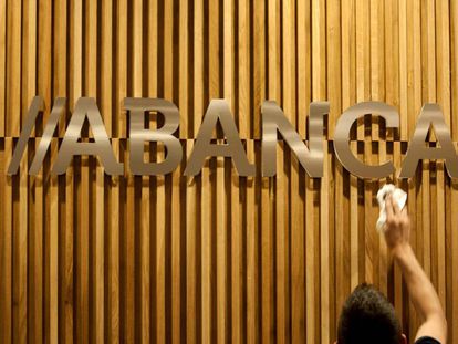 Un operario limpia en una oficina de Santiago el logotipo de Abanca. 