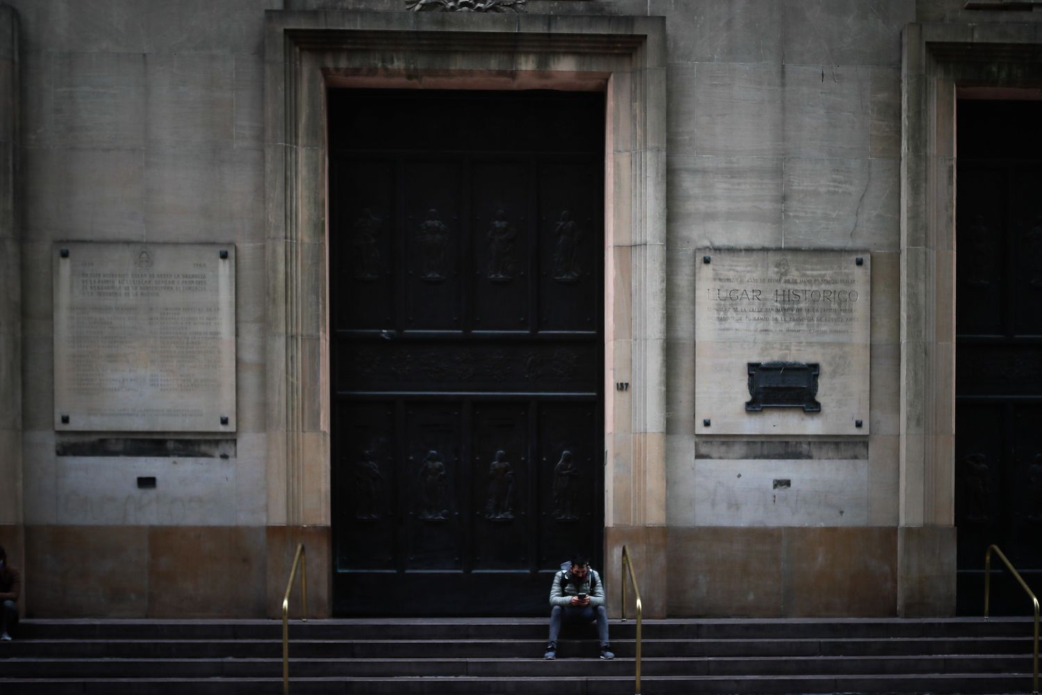 Un hombre espera sentado frente a la puerta de un banco este viernes 22 de mayo, en Buenos Aires.