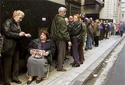 Pensionistas guardan cola frente al banco estatal para recibir su pensión mensual.