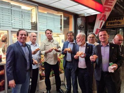El presidente Bolsonaro (tercero desde la izquierda) come una pizza con su comitiva, este domingo en Nueva York.