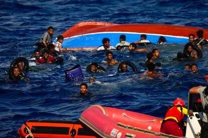 Varios migrantes se mantienen a flote sujetos a flotadores mientras durante el rescate. 