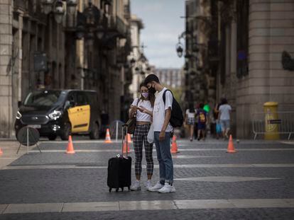 Dos turistas revisan su móvil en Barcelona.