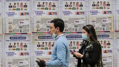 Una pareja pasa frente a una pancarta con información sobre las elecciones en Bogotá, el 10 de marzo.