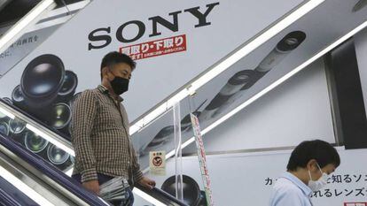 Dos personas pasan junto a una publicidad de Sony en una tienda en Tokio. 