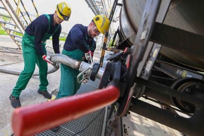 Dos trabajadores recibían el jueves aditivo líquido para el refinado de petróleo de un tren cisterna, al sur de Budapest (Hungría).