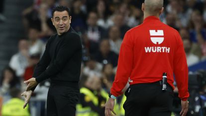 Xavi Hernández conversa con el cuarto árbitro en el clásico en el Santiago Bernabéu.