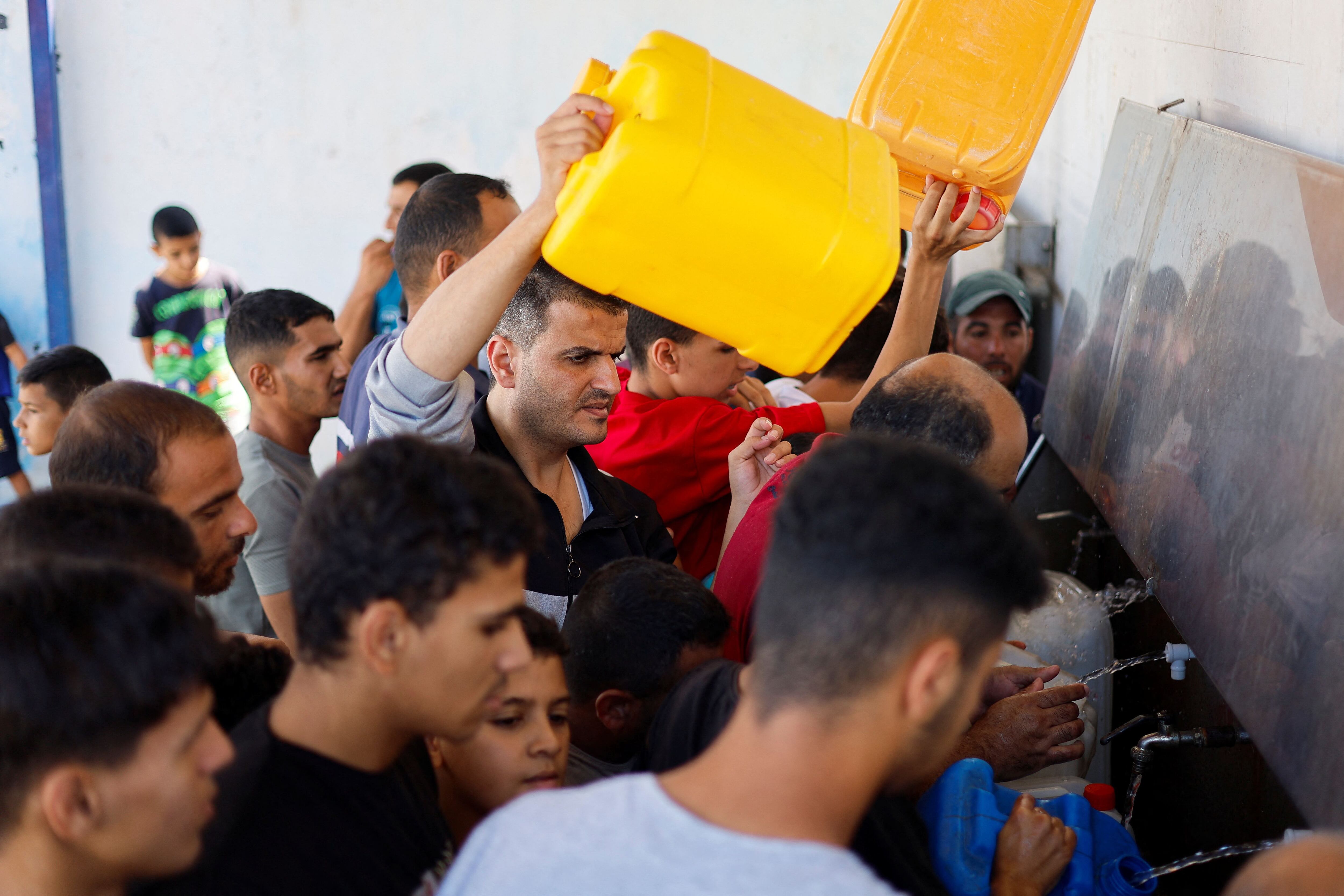 Un grupo de palestinos trata de recoger agua este domingo en Gaza.