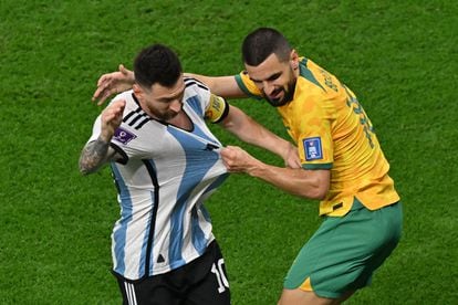 Australian defender Aziz Behich grabs Messi's shirt.