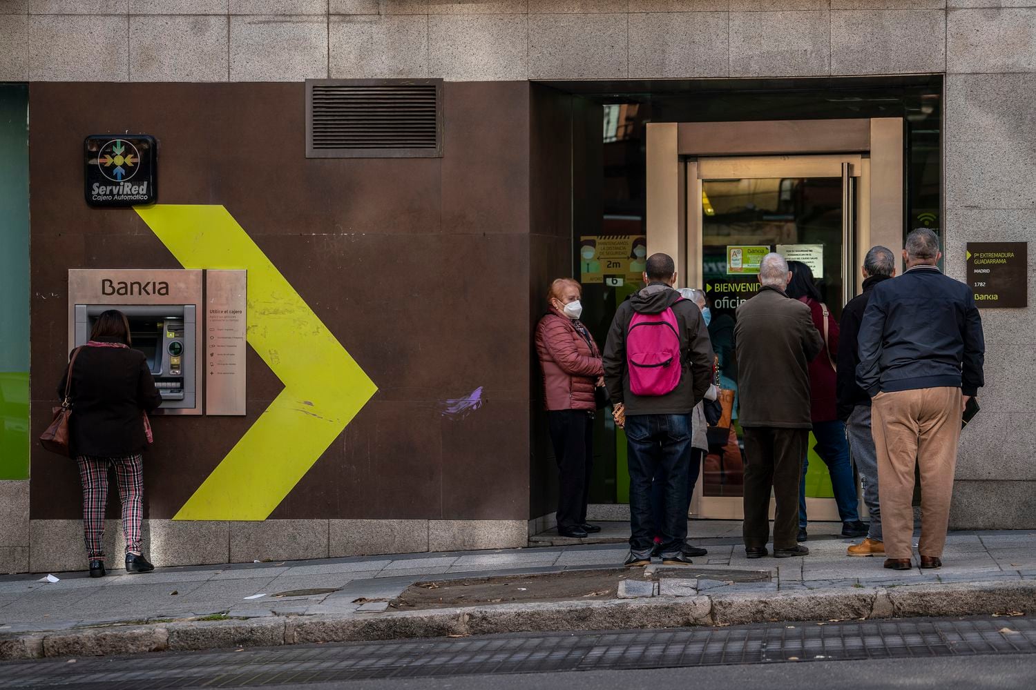 Un grupo de personas, esperando a entrar en una oficina bancaria.