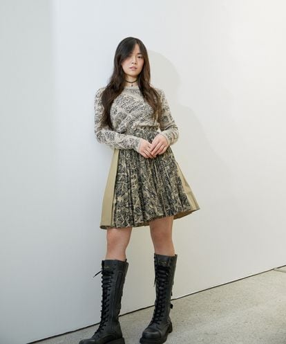 Xinyi Ye lleva jersey, falda, gargantilla y botas, todo de la colección Plan de Paris de DIOR.