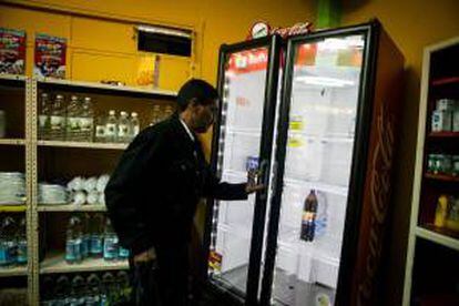 Un hombre abre una nevera mientras realiza compras en un abasto el 7 de junio de 2013, en Caracas. EFE/Archivo