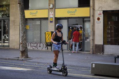 Una repartidora de Glovo, frente a un supermercado de la compañía de reparto en Barcelona.