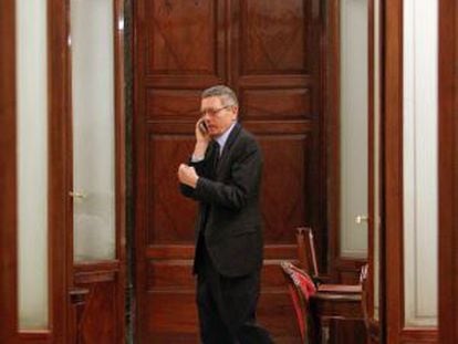 El ministro de Justicia, Alberto Ruiz-Gallardón, habla por el teléfono móvil en un pasillo del Congreso.