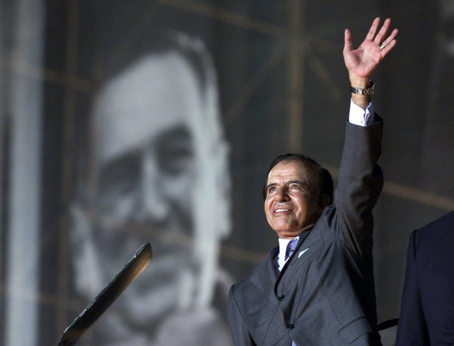 Carlos Menem saluda a sus simpatizantes, con un retrato del extinto presidente argentino Juan Domingo Perón como telón de fondo, en el estadio de River Plate, en abril de 2003.