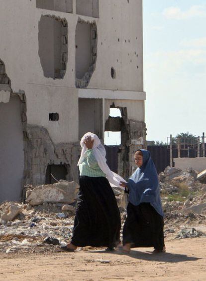 Dos mujeres palestinas caminan junto a los restos de una casa destruida en Rafah.