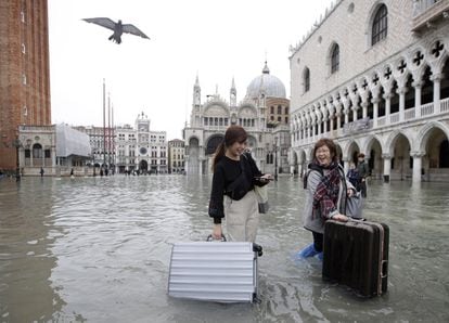 Dos turistas arrastran sus maletas en la inundada plaza de San Marcos de Venecia.