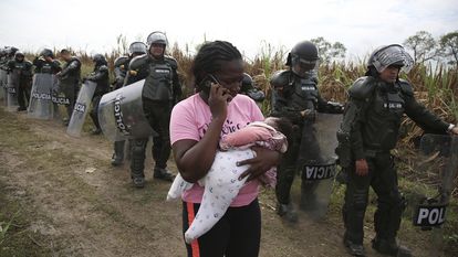 Una mujer sostiene a su bebé mientras la policía llega a los invasores desalojados de un terreno en Navarro, cerca de Cali, Colombia, el jueves 6 de octubre de 2022.