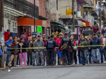 En una fotografía de septiembre de 2019, la policía municipal de Naucalpan (Estado de México) evita que vecinos se acerquen al cuerpo de un joven asesinado.