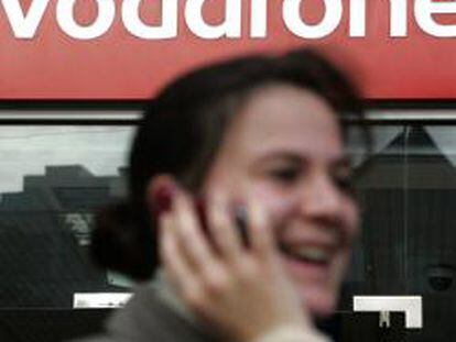 Mujer habla por teléfono delante de una tienda de Vodafone