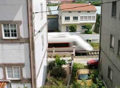 El tren pasa entre casas en Valga, a pocos metros de un paso a nivel.