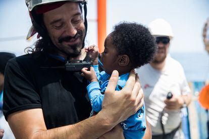 Un miembro del equipo de rescate sostiene en brazos a un niño.