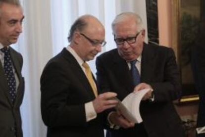 El presidente del comité de expertos para la reforma fiscal, Manuel Lagares (d), entrega al ministro de Hacienda, Cristóbal Montoro (c), el informe en la sede del Ministerio de Hacienda en Madrid.