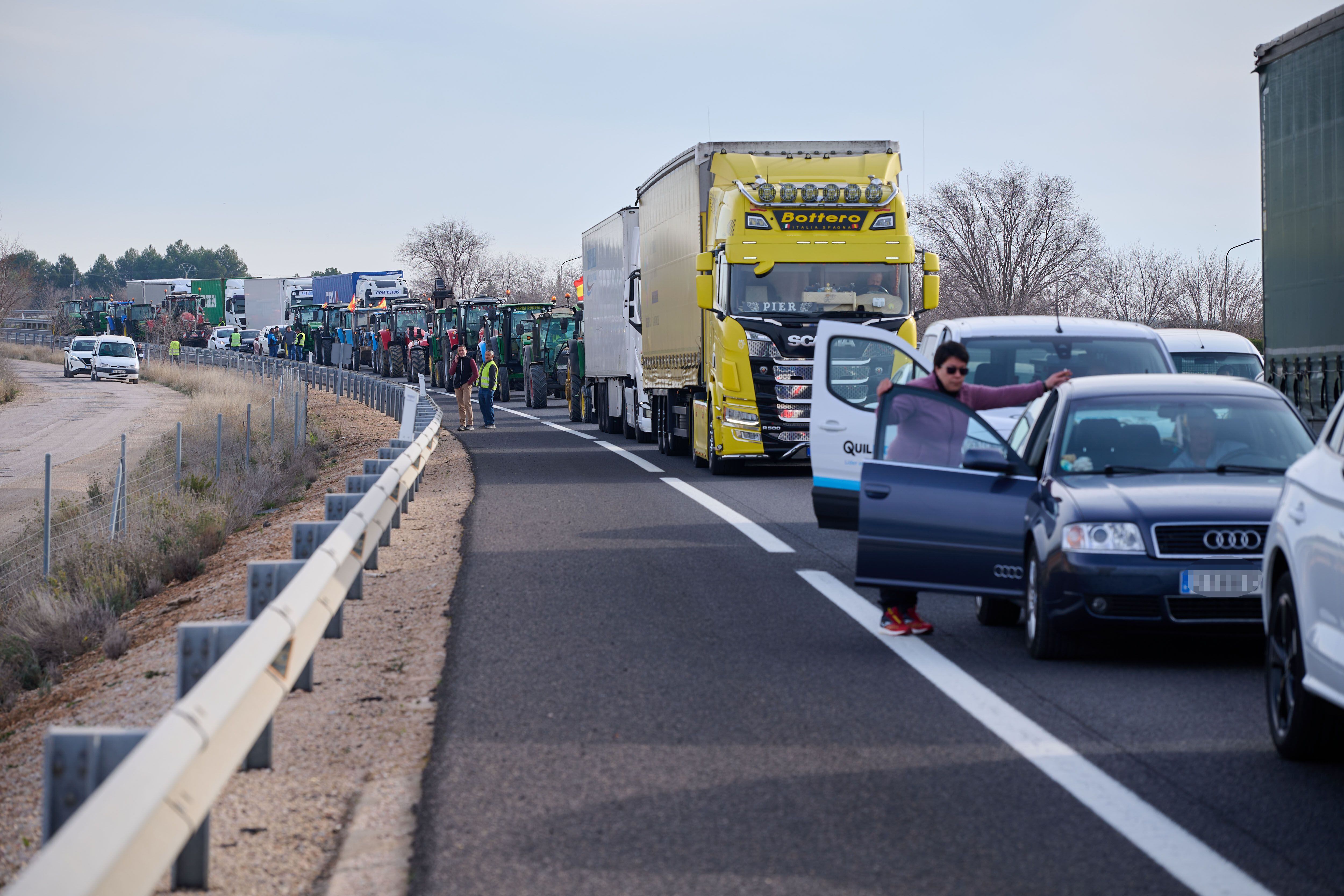 Varios vehículos detenidos por una concentración de tractores que se dirigen hacia el municipio de Manzanares por la autovía A-43, a su paso por la localidad de Tomelloso (Ciudad Real).