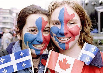 Dos jóvenes con las banderas y los símbolos en la cara de Canadá y Quebec.