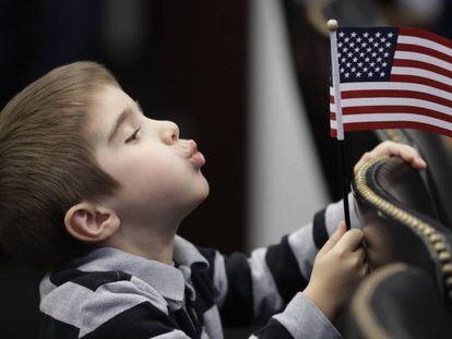 Un niño juega con una bandera de EE UU durante la ceremonia de naturalización de su madre. 