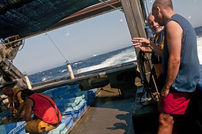 Sisco Sastre, patrón del Mèdan, da explicaciones a uno de los turistas que va en su barco. Al fondo, el resto de la tripulación clasifica el pescado.