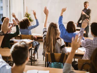 Unos alumnos levantan la mano para contestar a una pregunta.