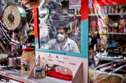 Un vendedor atiende espera clientes detrás de un plástico protector, durante la pandemia de covid en Ciudad de México.