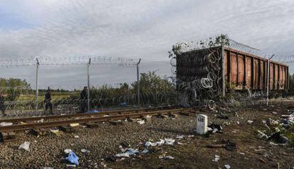 La policía húngara camina al lado de un vagón de ferrocarril cubierto de alambre en la frontera de Hungría con Serbia.