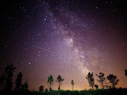 Un joven observa el cielo desde el concello coruñés de Monfero, con la Vía Láctea sobre su cabeza y con varios meteoros de las conocidas como Perseidas.
