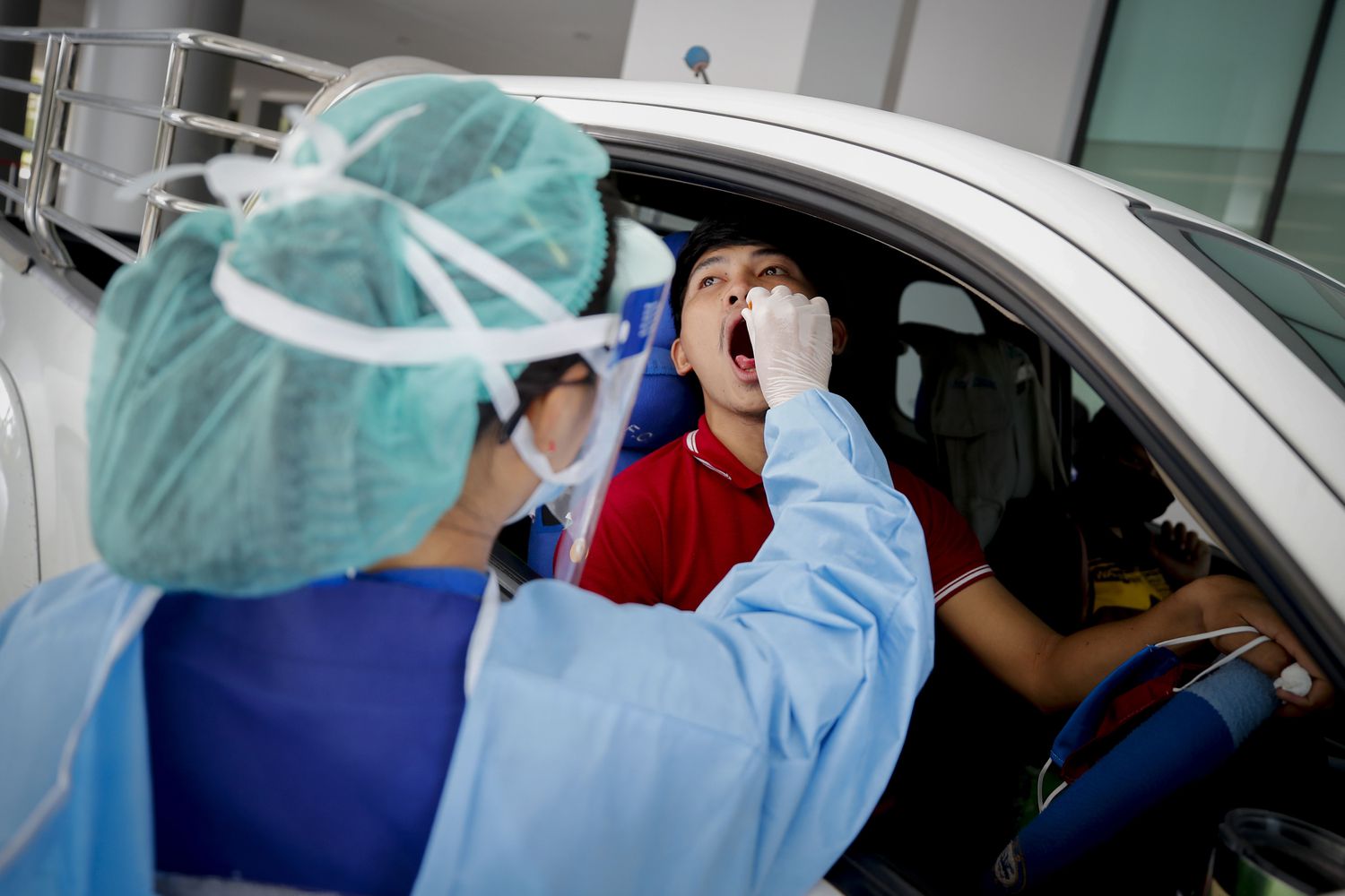 Un médico con material de protección extrae una muestra a un conductor para detectar la Covid-19 en un hospital de Bangkok.