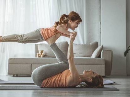 Una madre y su hija hacen ejercicio en su casa. 