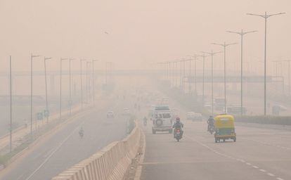Vehículos circulan entre la niebla mezclada con humo en Nueva Delhi (India).