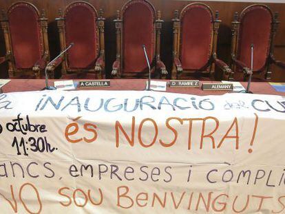 Pancarta de protesta sobre la mesa de autoridades que deb&iacute;a presidir el acto de inauguraci&oacute;n