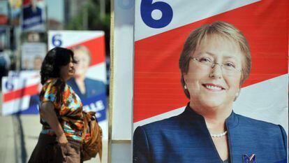Una mujer camina al lado de la propaganda pol&iacute;tica de Bachelet. 
