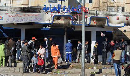 Un grupo de personas permanece en el exterior de un supermercado saqueado en la capital tunecina.