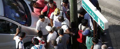 Un grupo de hombres ofrece sus servicios a un reclutador de braceros junto a la plaza Elíptica.