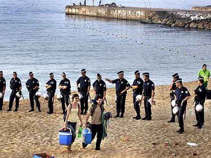 Cordón de la Guardia Urbana en la playa de Bogatell, ayer a primera hora de la mañana, para iniciar la limpieza.
