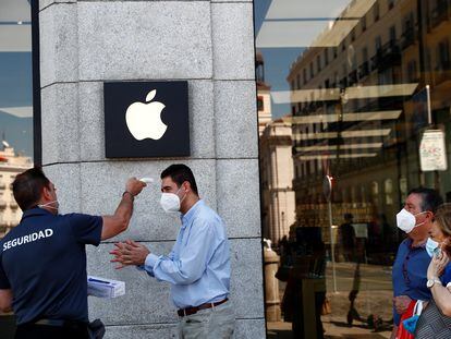 Un hombre toma la temperatura en la entrada de una tienda de Apple en Madrid, el 30 de junio.