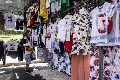 Un niño intenta alcanzar a una prenda en un puesto del mercadillo de Villaverde.