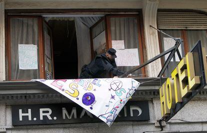 Un agente retira una pancarta del hotel Madrid tras el desalojo de los 'okupas'.