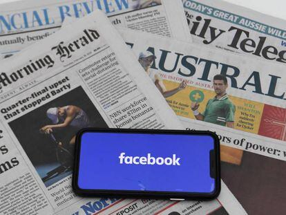 El logo de Facebook en un móvil junto a periódicos australianos. 