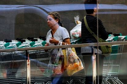 Una cliente sale de un supermercado en Valencia con la compra en bolsas de plástico.